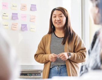 A student stands in front of a class giving a presentation